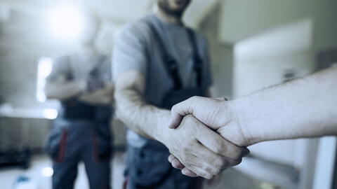 Zwei Fachhandwerker geben sich die Hand auf der Baustelle