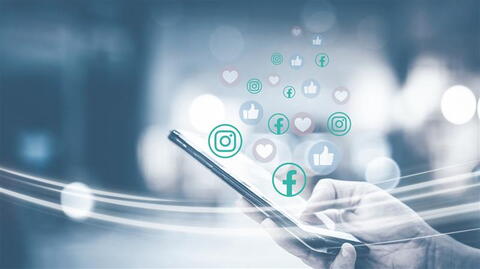 Hand hält ein Smartphone in der Hand, aus dem Likes und Herzen fließen