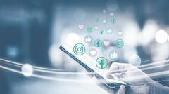 Hand hält ein Smartphone in der Hand, aus dem Likes und Herzen fließen